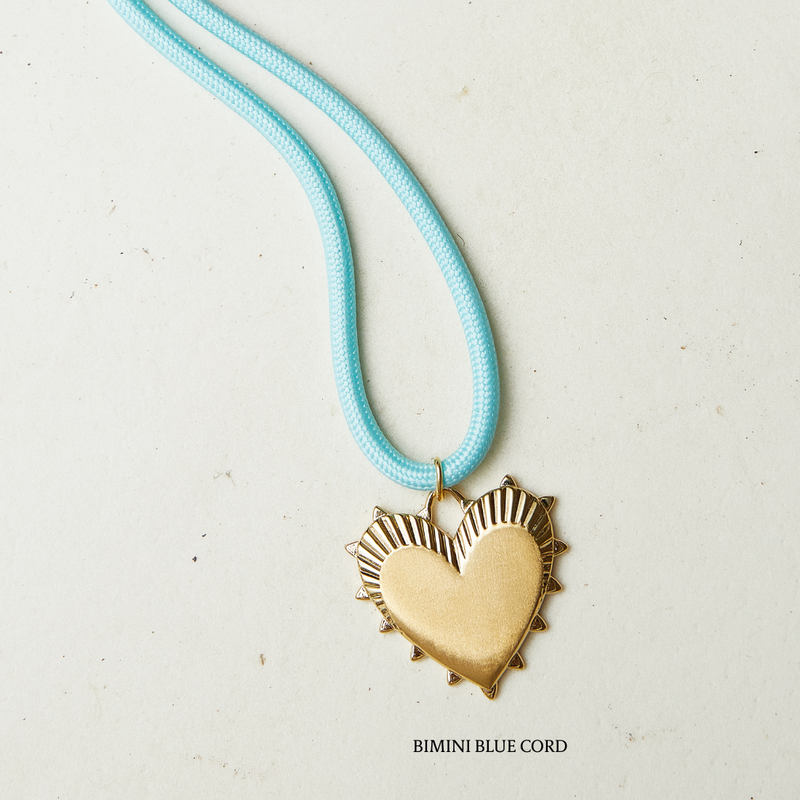 Necklace with a gold heart pendant on a light blue cord against a white background