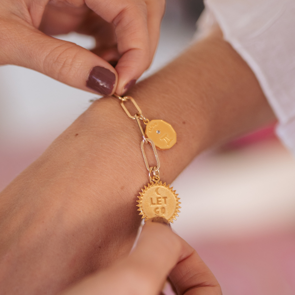 Woman placing charm bracelet on hand with Let Go Charm