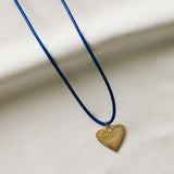 Navy Cord with Ribbed Heart of Gold Charm laying on a piece of fabric
