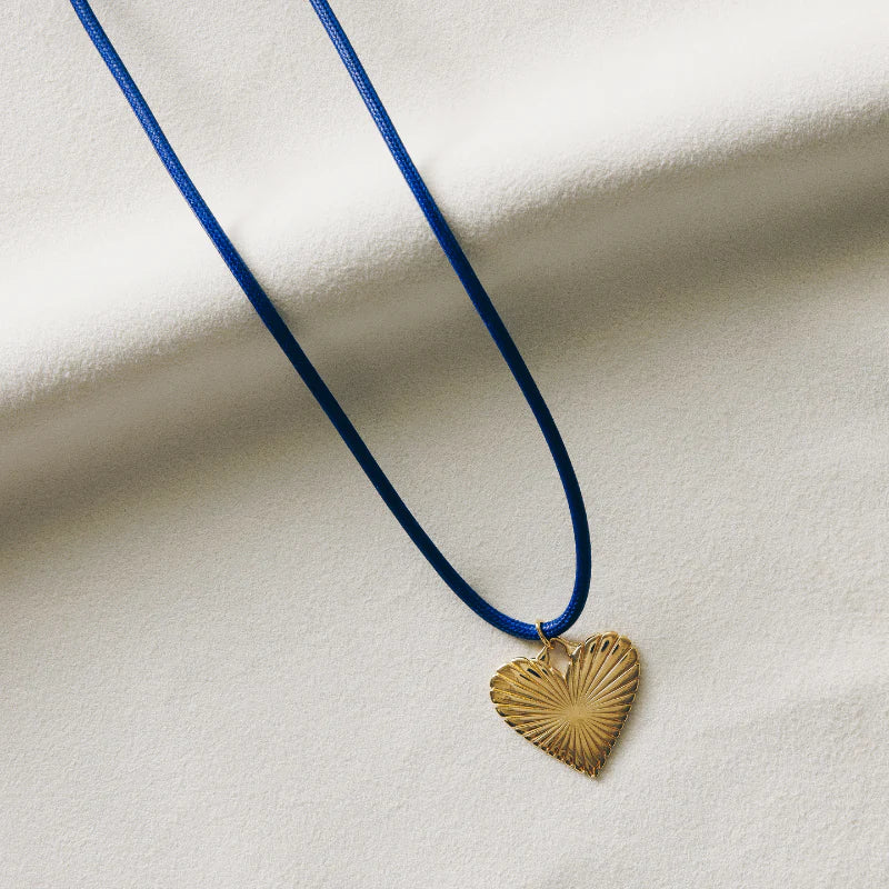 Navy Cord with Ribbed Heart of Gold Charm laying on a piece of fabric